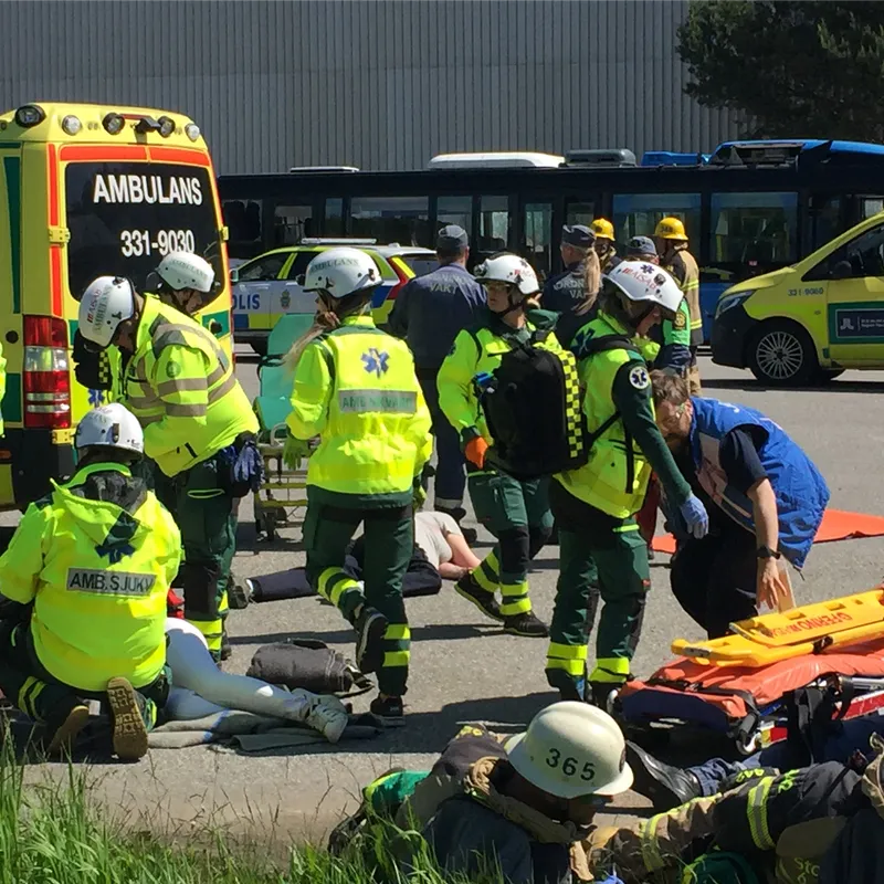 Ambulanspersonal och andra räddningsaktörer arbetar tillsammans på en skadeplats.